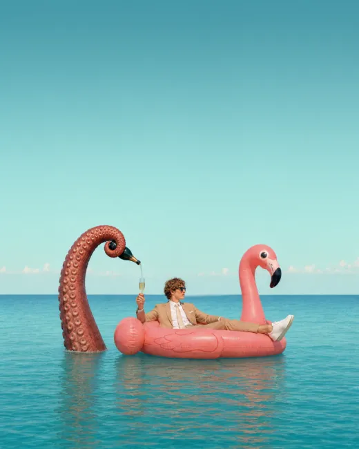 Mann auf einer Flamingo-Luftmatratze mit rosa Flamingo und Oktopus